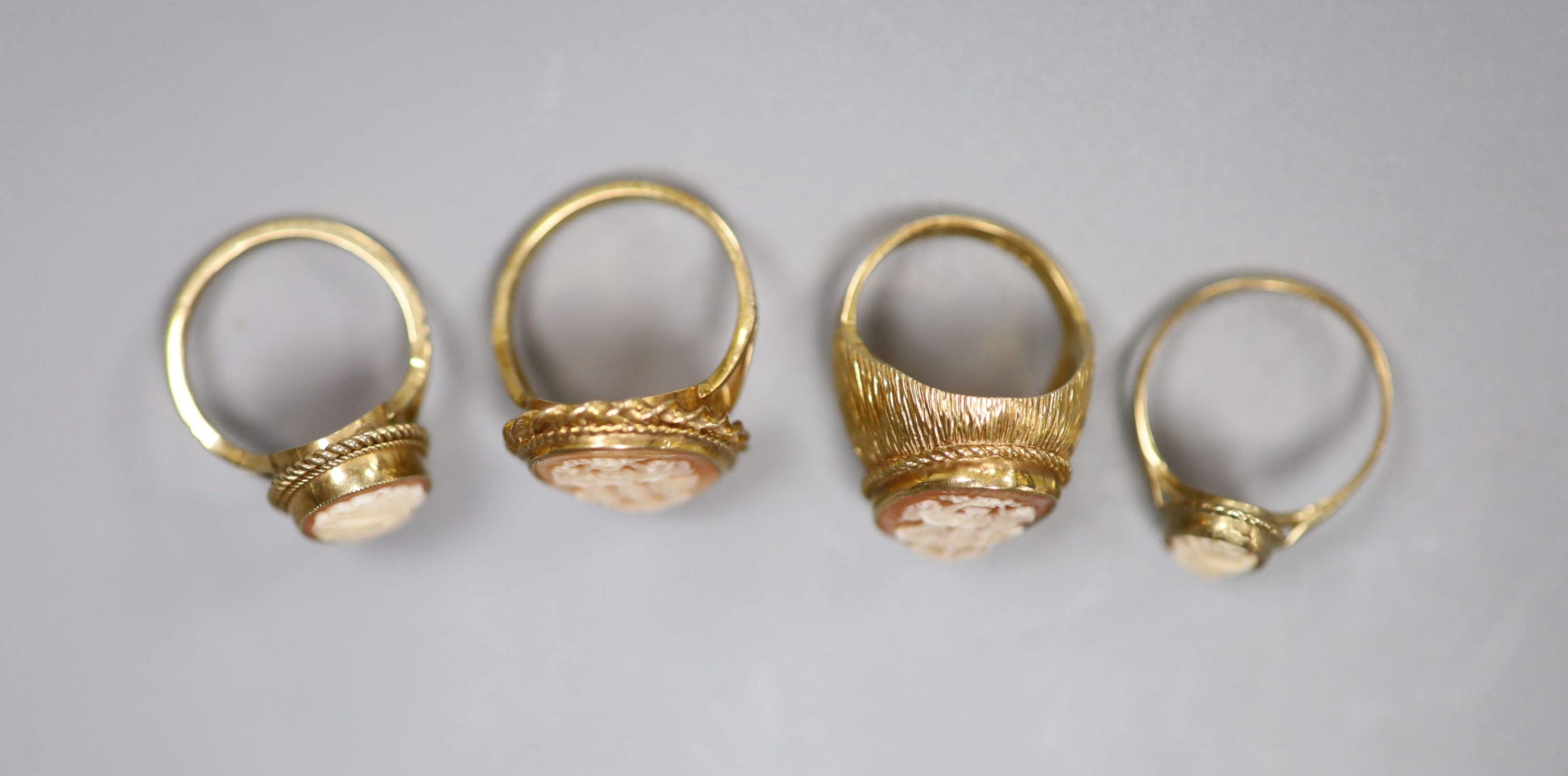 Four assorted modern 9ct and cameo shell dress rings including one carved with The Three Graces